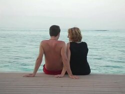 MS, Cayman Islands, Grand Cayman, Young couple sitting on pier, rear view Stock Footage