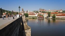 Citizens use the Charles Bridge to cross the River Vltava as ferryboats sail beneath. Stock Footage