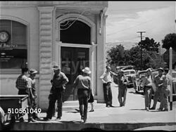 1945: CALIFORNIA: AGRICULTURE TOWN: HA WS Town w/ planted fields beyond town. VS Men standing on sidewalk socializing outside Bank of America Morgan Hill Branch building, VS Men talking in small groups, man & boy entering bank, senior male walking out Instructional Video