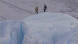 Two explorers hike across a glacier. Stock Footage