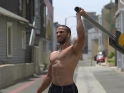 A man working out in an urban alley, doing shoulder press with a road barricade bar. - Slow Motion Stock Footage
