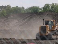 Caterpillar construction vehicles drive through a construction site Stock Footage