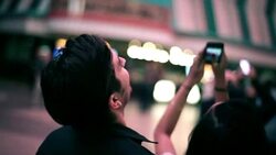 Young couple gaze up at the light-show in downtown Vegas, young woman takes pictures with smartphone Stock Footage