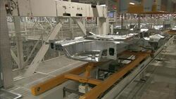 Automated machines assemble car parts, and then a conveyor moves the parts along. Stock Footage