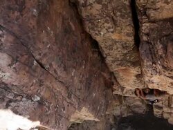 Handheld tilt of a rock-climber slowly picking himself up a wall. Stock Footage