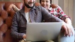 young couple sitting on sofa and using laptop Stock Footage