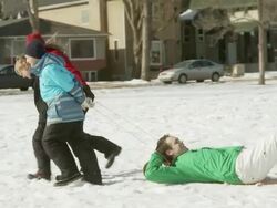 Family pulls dad on a tobaggan Stock Footage