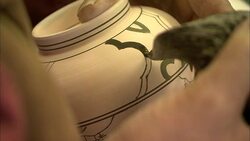 An artist paints a finely detailed design on a piece of pottery. Stock Footage