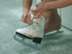 A female figure skater lacing up skates Stock Footage