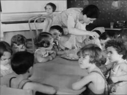 B/W 1934 children sitting at table being served snack in nursery school / WPA project / newsreel Stock Footage