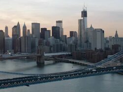 Aerial over East river of downtown Manhattan and bridges at sunset Stock Footage
