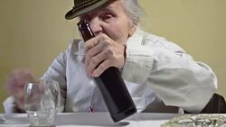 Elderly woman opens bottle of dark beer. Stock Footage
