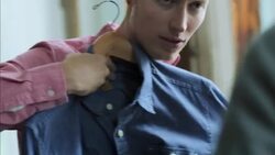 Young man holds up denim shirt and chats with shop worker in clothing store Stock Footage