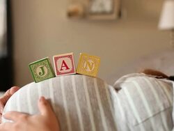 A pregnant women using blocks to spell the month of JAN on her stomach. Stock Footage