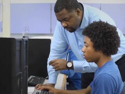 Teacher Assists Male Student in Computer Lab Stock Footage