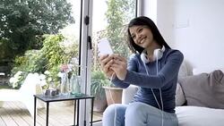 Beautiful brunette taking a selfie at home with smartphone Stock Footage