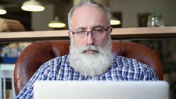 Adult senior bearded man sitting with a laptop Stock Footage
