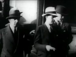 B/W 1930s PAN police leading Legs Diamond on sidewalk Stock Footage