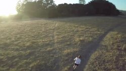 AERIAL woman jogging in field, rounding sharp corner Stock Footage