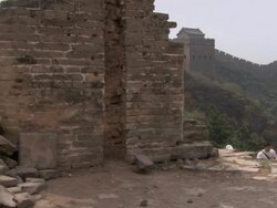 A crumbling portion of the Great Wall of China, then panning to the right to reveal a long line of people walking the length of the Great Wall.  Stock Footage