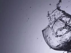 CU SLO MO Shot of wave of water with ice cube splashes into wine glass / United Kingdom Stock Footage