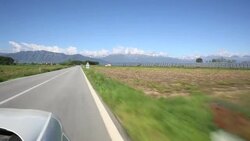 POV from car driving along a countryside road with mountains in the distance Stock Footage