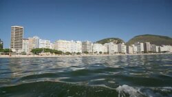 Tracking shot of Copacabana beachfront skyline from boat over glassy water Stock Footage