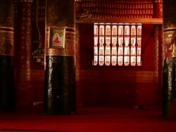 MS Shot of richly decorated dark red and gold interior of Buddhist temple with man walking away / Luang Prabang, Laos Stock Footage