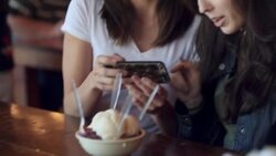 Two young women take smartphone photos of ice cream sundae Stock Footage