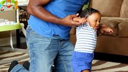 MS Father helping infant son learn to walk in living room Stock Footage