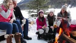 Multi-generation family toasting marshmallows over fire pit on snowy patio Stock Footage
