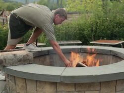 MS Man placing logs on fire in outdoor fire pit / Vermont, United States Stock Footage