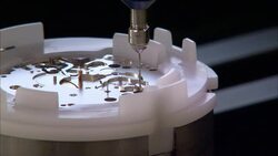 An automated carousel rotates a watch component below a mechanical crafting tool at a watchmaking factory. Stock Footage