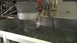 Water pours over rollers that stretch plastic trimming line in a factory. Stock Footage