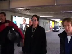 Ozzy Osbourne walks down airport corridor after arriving at Heathrow Stock Footage