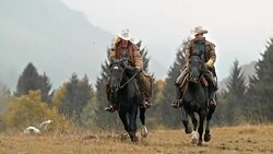 SLO MO DS Couple galloping on their horses across meadow Stock Footage