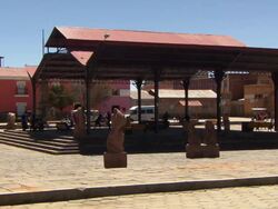 Children playing under metal canopy in public square on sunny day, Tiwanaku Tiahuanaco/Tiahuanacu, Bolivia Stock Footage