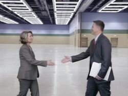  MS Two business associates meet, shake hands, then exit together in middle of a large empty room / Seattle, Washington, United States Stock Footage