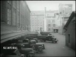1937: REPUBLIC OF FINLAND: CO-OPERATIVE WORK: Truck backing in w/ others into loading dock. VS Male workers sitting outside cafe at umbrella topped tables, some w/ food on trays, male eating, one reading paper & smoking cigarette. Meal, lunch, break Instructional Video