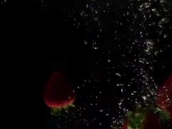 Strawberries falling into water, black background Stock Footage