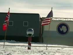 MS of sphere at ceremonial South Pole with Amundsen Scott South Pole station and US, Norwegian flags / South Pole, Antarctica  Stock Footage