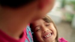 Young hispanic girl laughs in older brother's arms Stock Footage
