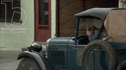 Car driving through town, 1930s - reenactment Stock Footage