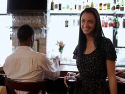 MS Young  woman standing at  bar with friends sitting behind her drinking cocktails / Minneapolis, Minnesota, United States Stock Footage
