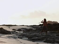 MS Rasta man standing on volcanic rock spinning poi balls with ocean / Montezuma, Punteranes, Costa Rica Stock Footage
