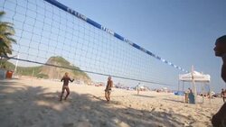 Brazilian footvolley teams kick and head soccer ball back and forth over net in intense beach match Stock Footage