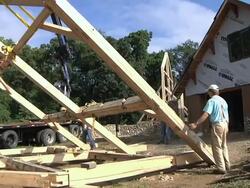 WS Carpenters slowly moving part of structure during framing of an energy efficient post / Grass Lake, Michigan, USA  Stock Footage