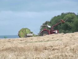 MS Bale of straw and tractor with baling press in grass field / Serrig, Rhineland-Palatinate, Germany Stock Footage