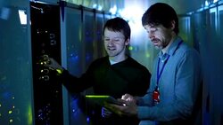 Server room technicians using digital tablet at server panel Stock Footage
