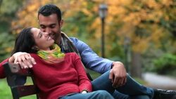 New York couple recline and nuzzle on park-bench in the heart of Central Park in fall Stock Footage